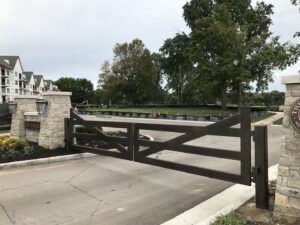 A large ornamental metal entrance gate with stone pillars installed by Roy & Son Fencing in Lee's Summit, MO.