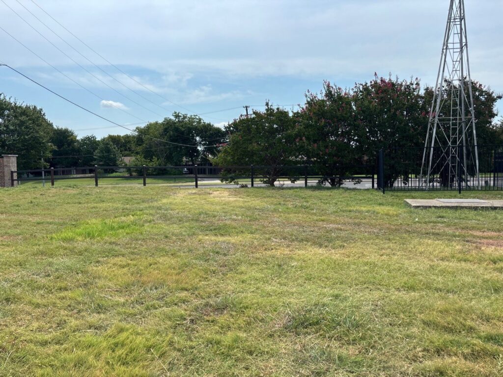 An ornamental black metal fence installed along a property line in a large grassy area by BAR Z Fencing and Welding LLC in Midlothian, TX