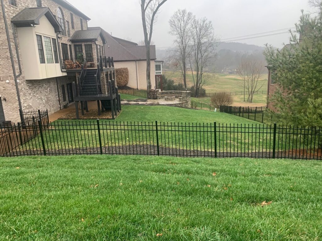 A black ornamental metal fence installed on a sloped backyard property by America's Fencing in Nashville, TN.