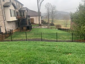 A black ornamental metal fence installed on a sloped backyard property by America's Fencing in Nashville, TN.