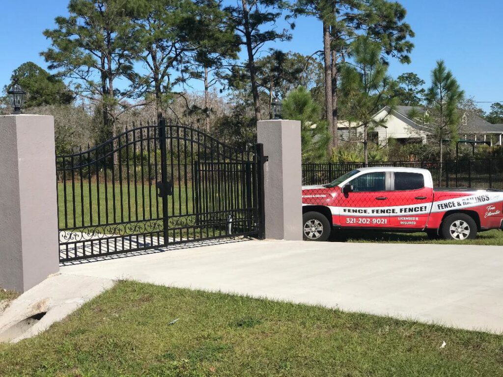 An elegant ornamental wrought iron driveway gate with stone pillars installed by Fencing & Railing 2 Corp in Orlando, FL.