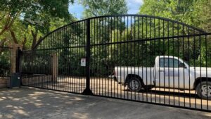 An ornate arched iron driveway gate installed by Iron Fence Services, LLC in Lancaster, TX.