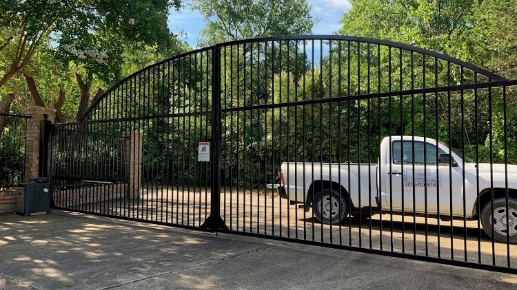 An ornate arched iron driveway gate installed by Iron Fence Services, LLC in Lancaster, TX.