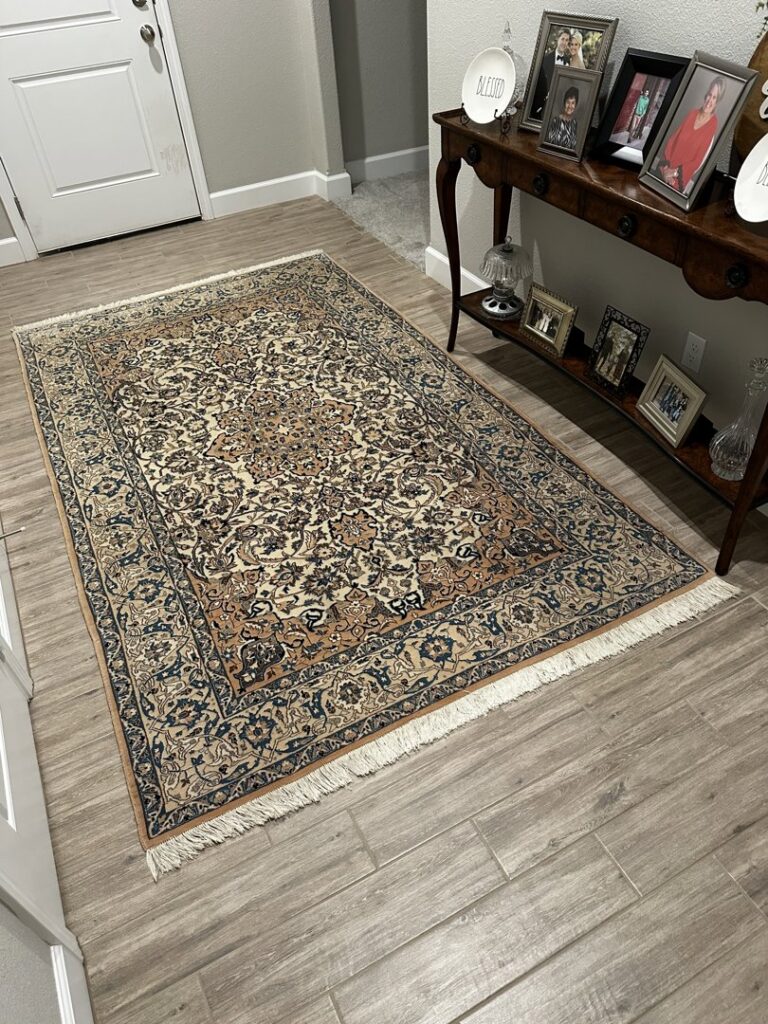 An ornate patterned area rug with fringe displayed on a wooden floor in a home hallway by Accents Galleria in Kansas City, MO