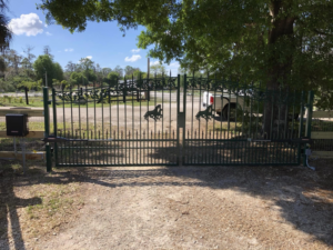An ornate green automatic driveway gate with horse designs installed by Big Bear Automatic Gates, LLC in La Belle, FL.