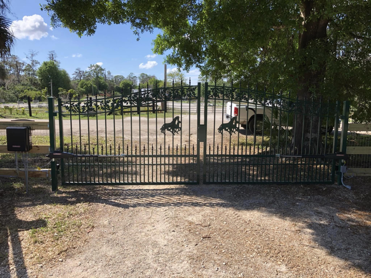 An ornate green automatic driveway gate with horse designs installed by Big Bear Automatic Gates, LLC in La Belle, FL.