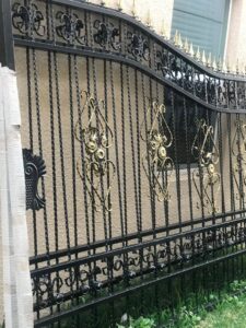 A close-up of an ornate black and gold wrought iron gate, showcasing craftsmanship by Fencing & Railing 2 Corp in Orlando, FL.