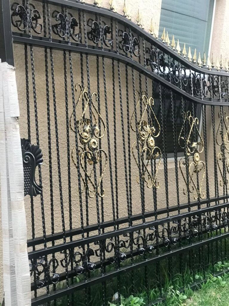 A close-up of an ornate black and gold wrought iron gate, showcasing craftsmanship by Fencing & Railing 2 Corp in Orlando, FL.