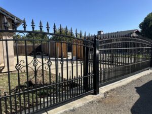 An ornate black iron driveway gate, showcasing the craftsmanship of Exclusive Custom Iron Works in Stockton, CA.