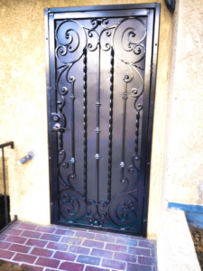 An ornate black iron security door with scrollwork installed at a home by HBHB Iron Works in Los Angeles, CA.