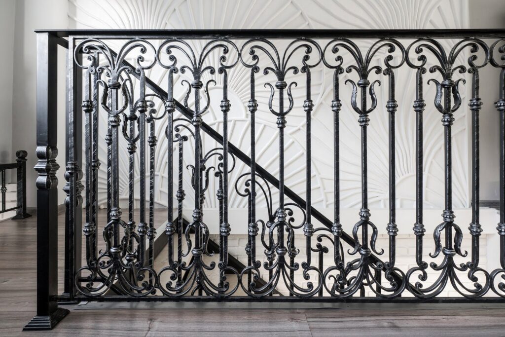 An ornate black iron stair railing with decorative scrollwork installed by Ironcraft Welding in Chicago, IL.