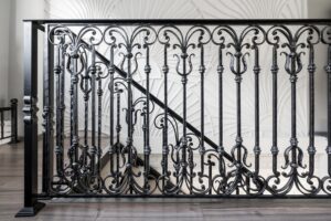 An ornate black iron stair railing with decorative scrollwork installed by Ironcraft Welding in Chicago, IL.