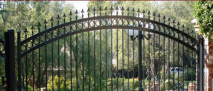 An ornate black metal arched driveway gate with decorative elements, installed by Colorado Fence and Gate Systems in Colorado Springs, CO.