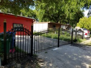 An ornate black metal fence with decorative gold finials and a double gate installed by Serrato's Fence & Welding in San Antonio, TX.