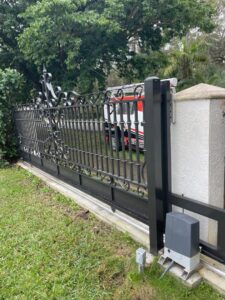 An ornate black sliding gate with a gate operator motor installed by Motor & Fence Solutions in Miami, FL.