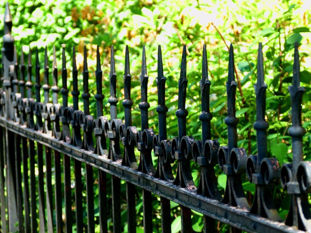 A close-up of an ornate black wrought iron fence with decorative finials by Sumter Fence Company in South Sumter, SC.