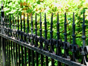 A close-up of an ornate black wrought iron fence with decorative finials by Sumter Fence Company in South Sumter, SC.