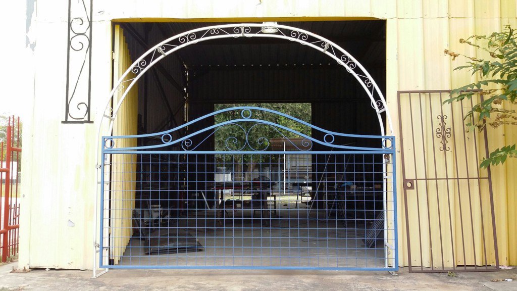 An ornate blue and white metal gate, likely in fabrication or repair, showcasing the welding work of Serrato's Fence & Welding in San Antonio, TX.