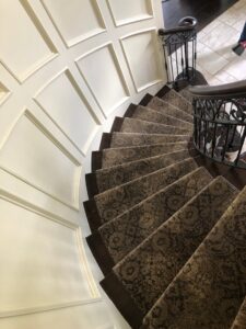 An ornate patterned carpet runner expertly installed on a curved staircase by AguirreFloorz in Colorado Springs, CO.