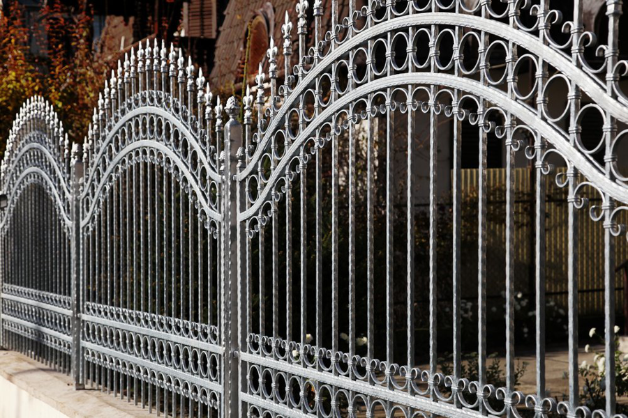 An elegant and ornate grey wrought iron fence with decorative scrollwork by New Bedford Fence in New Bedford, MA.