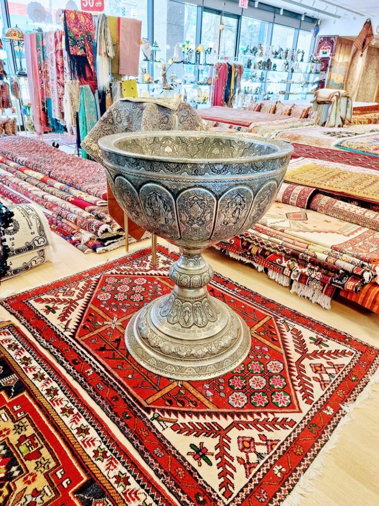 An ornate metal bowl displayed on a beautiful Persian rug at Art Of Persia, a carpet contractor in Portland, OR.