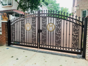An ornate metal driveway gate with frosted panels installed by Elite Ornamental Fence LLC in Paterson, NJ.