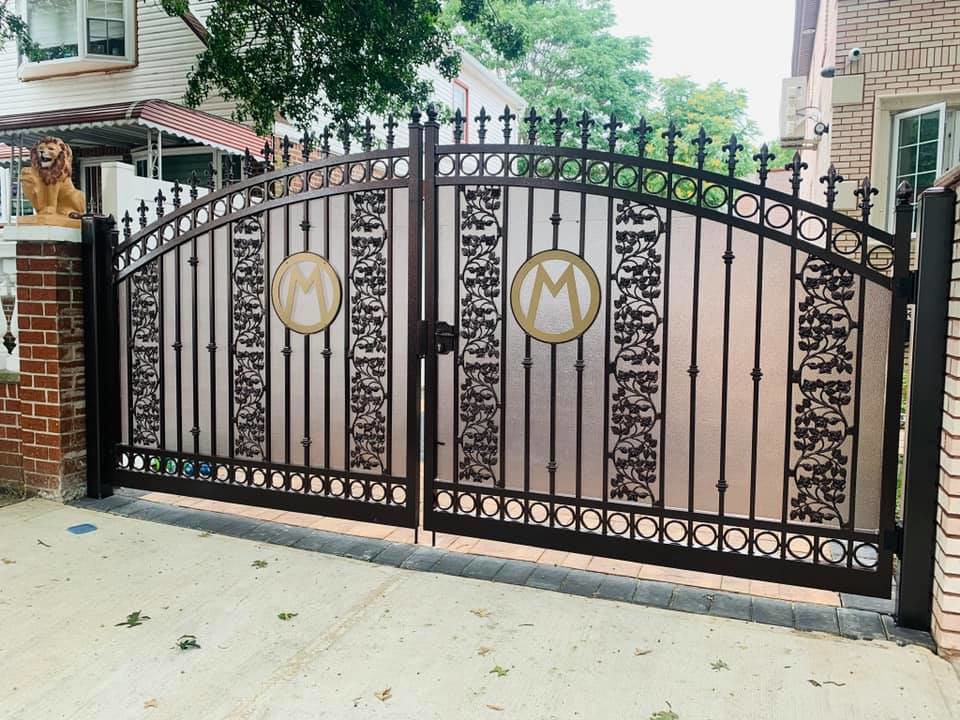 An ornate metal driveway gate with frosted panels installed by Elite Ornamental Fence LLC in Paterson, NJ.