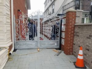 Workers installing an ornate metal driveway gate for a residential property by Excel Gates & Services Inc. in New Haven, CT