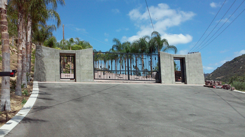 An ornate metal entry gate with concrete pillars installed by Automated Entry Systems Inc in Escondido, CA.