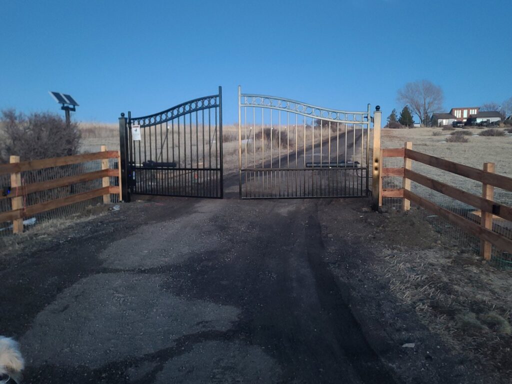 Two ornate metal gates, black and silver, with wooden split-rail fences installed by First Rate Fence & Supply in Denver, CO.