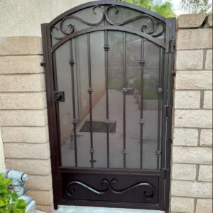 An ornate brown metal pedestrian gate with a screen, installed by Portugal's IronWorks in Los Angeles, CA.