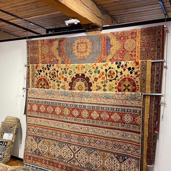Beautiful ornate Persian-style rugs displayed vertically on racks in the showroom of Adiva Rugs in Chicago, IL.