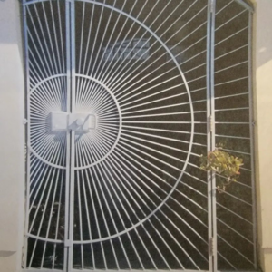 An ornate metal security gate featuring a radial design, crafted by Fierro Iron Works Inc. in San Francisco, CA.