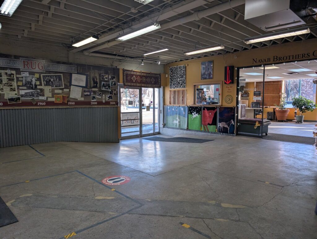 An ornate red and black patterned rug displayed on a wooden floor by American Rug Laundry in Saint Paul, MN.