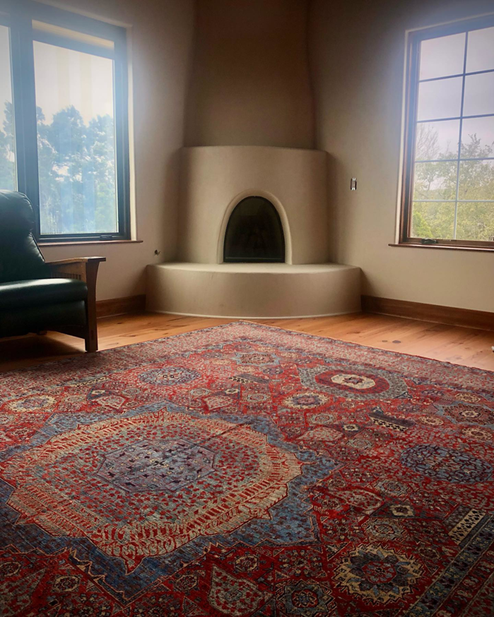A beautiful ornate red and blue area rug laid out in a room, showcasing a product from David Alan Rugs in Austin, TX.