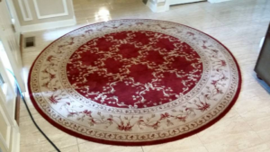 An ornate round red and beige area rug on a tiled floor, cleaned by 1 Chicago Carpet Cleaner in Plainfield, IL.