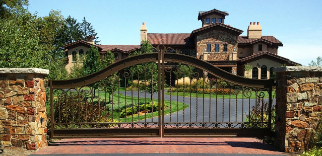 Ornate wrought iron driveway gate with stone pillars installed by Gate Options in West Chicago, IL