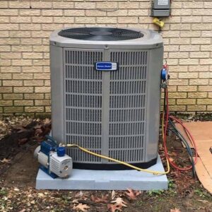 An outdoor AC condenser unit being serviced with a vacuum pump and manifold gauges by TAG Heat N Air in North Little Rock, AR.