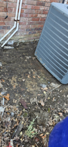An outdoor AC condenser unit next to a brick wall, serviced by Anubis Mechanical in Goose Creek, SC.