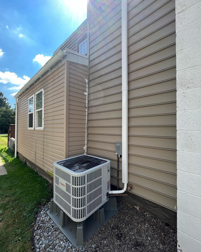 An outdoor Bosch air conditioning condenser unit installed next to a house by Naugher Heating and Cooling in Lancaster, PA