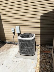 An outdoor air conditioning condenser unit next to a residential building, installed or serviced by Golden Heating and Air LLC in Arvada, CO.