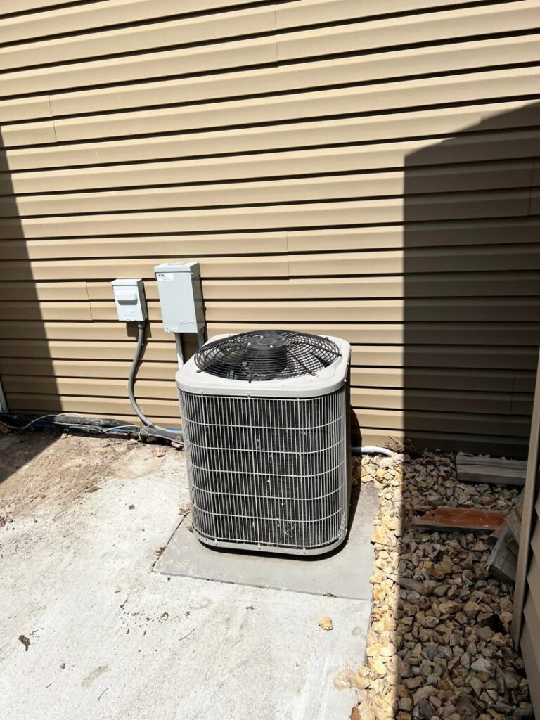 An outdoor air conditioning condenser unit next to a residential building, installed or serviced by Golden Heating and Air LLC in Arvada, CO.