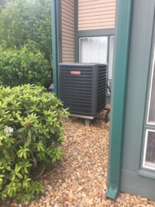 An outdoor Goodman AC condenser unit installed next to a building by R&M Mechanical Services LLC in Milford, CT.