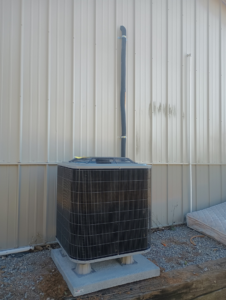New outdoor AC condenser unit installed next to a metal building by Air Prime OKC in Oklahoma City, OK