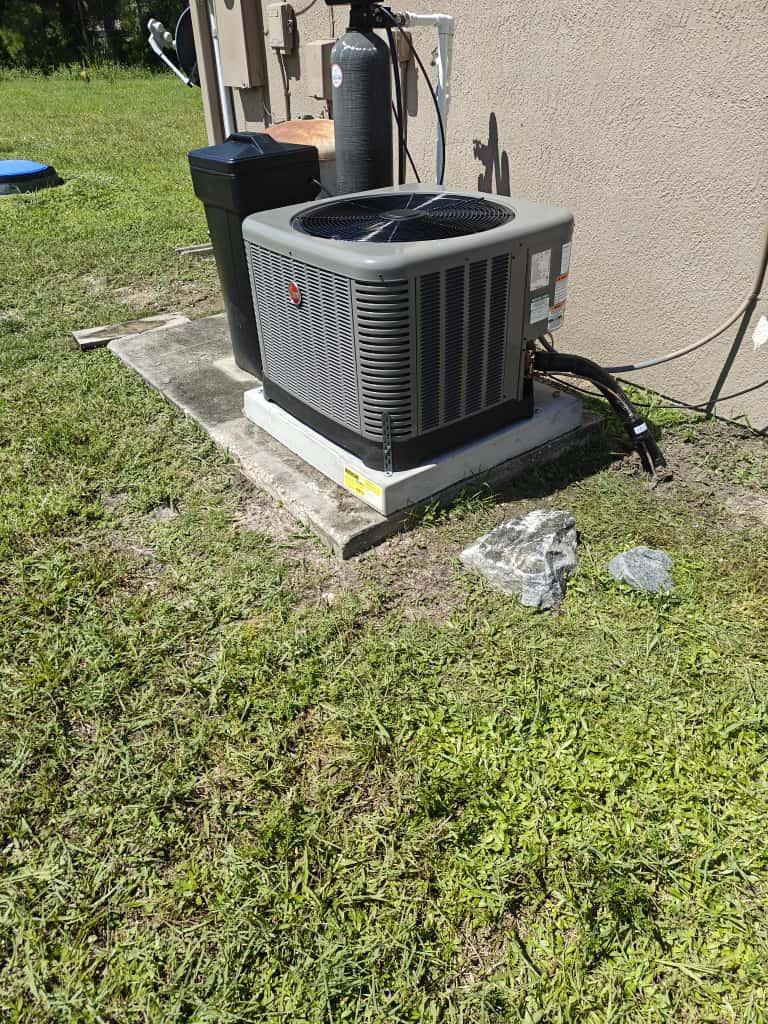 An outdoor AC condenser unit installed on a concrete pad by QUICK AIR USA in Orlando, FL.