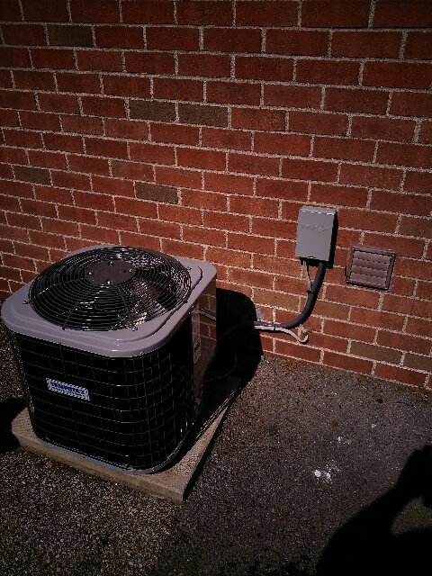 An outdoor AC condenser unit installed next to a brick wall by R. Davis Mechanical in Pittsburgh, PA