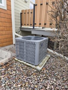 An outdoor AC condenser unit installed on a concrete pad in a rock landscape by 406 Heating & Cooling LLC in Missoula, MT.
