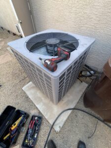 An outdoor AC condenser unit being serviced by Sun Devil Heating & Cooling INC in Peoria, AZ, with tools visible.