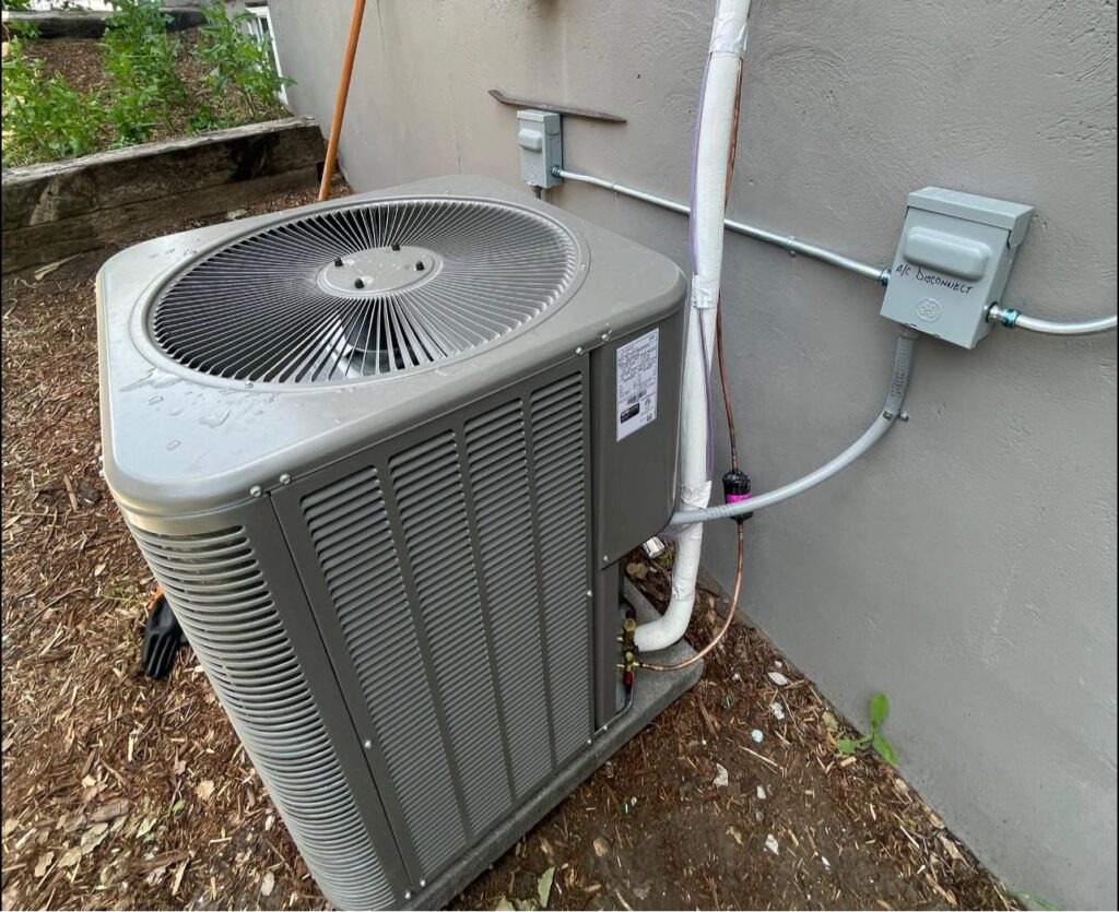 An outdoor air conditioning condenser unit with visible wiring and conduit installed by CHAMPS Heating&Air in Denver, CO