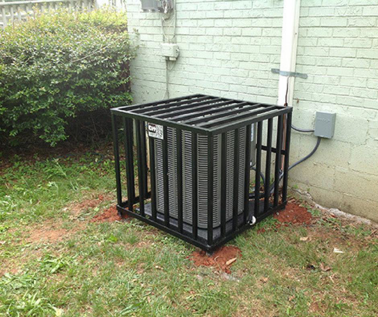 An outdoor AC condenser unit protected by a metal cage, showcasing HVAC installation and security by MBI Heating and Air Conditioning in Allentown, PA.